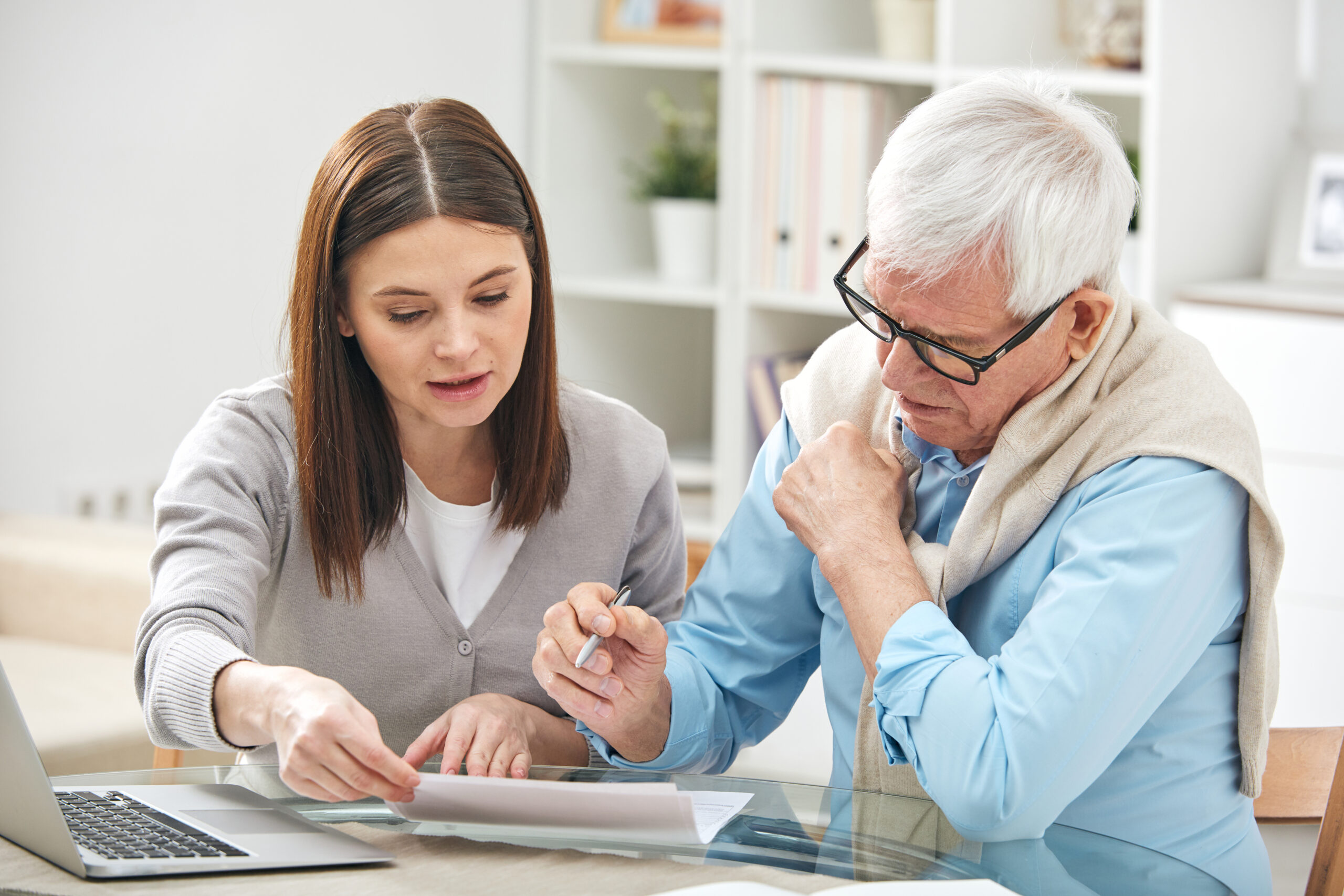 young female explaining her senior father how to fill in paper