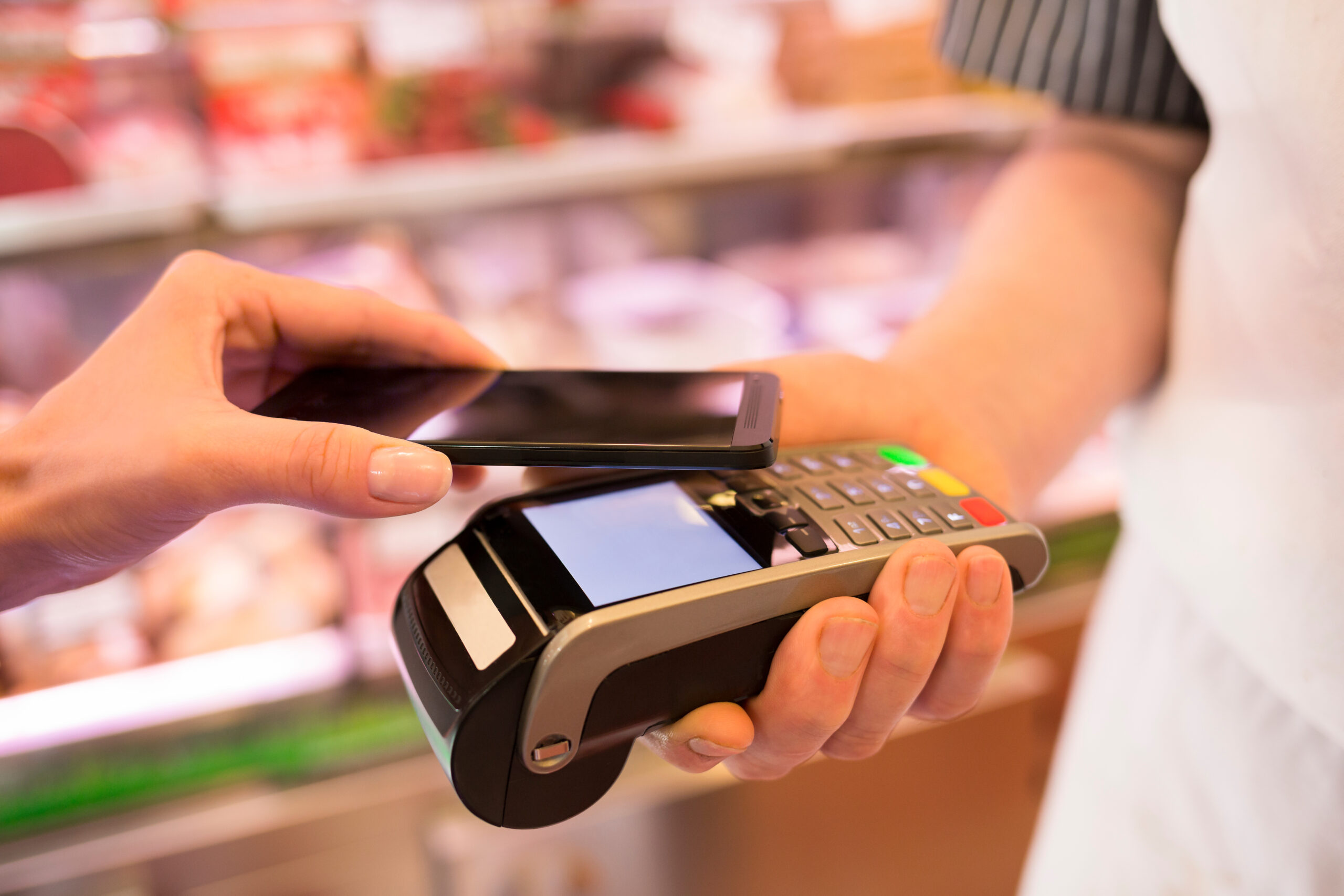 woman paying with nfc technology on mobile phone, in supermarket