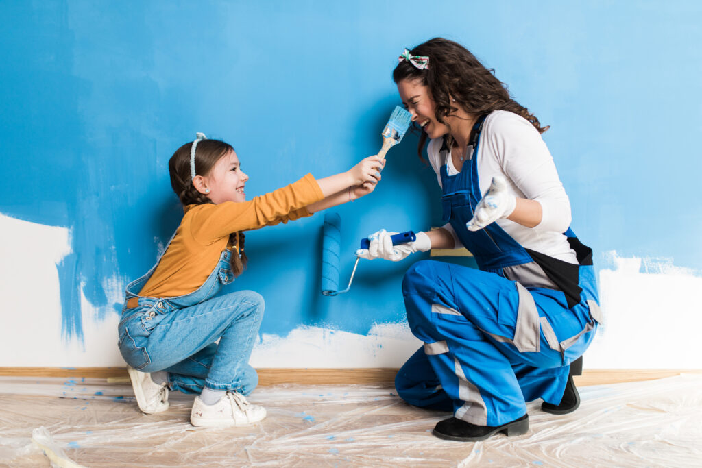 mother and daughter enjoying together while painting wall.