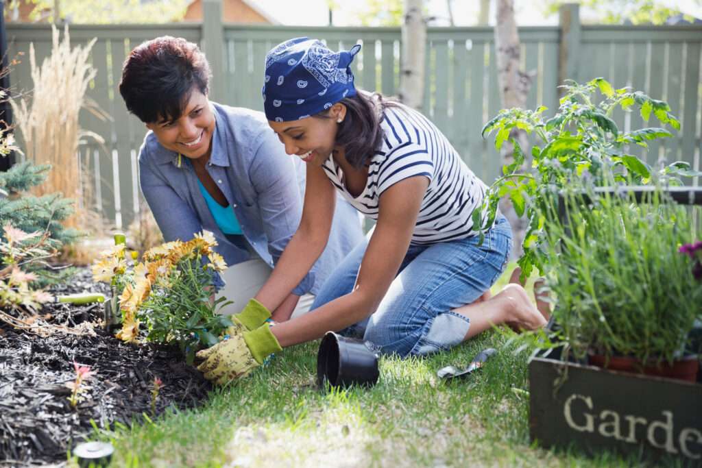 mother and daughter planting flowers in yard